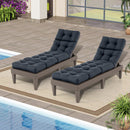 Two wicker lounge chairs with DirectDeals Outdoor Lounge Chaise Cushion Set of 2 - 73x22 Inch High Back in dark gray sit side by side on a rug by the pool, near a modern house with large windows and potted plants.