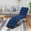 A DirectDeals Outdoor Lounge Chaise Cushion Set of 2 - 73x22 Inch High Back in blue rests on a patterned rug in a chic living room with a sofa, striped pillows, wooden table, and plants.