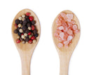 Two wooden spoons on a white background—one showcasing the vibrant blend of black, white, and red mixed peppercorns from The Spice Lab’s Premium Kings Pepper Grinder included in The Spice Lab Himalayan Pink Salt & Premium Kings Pepper Grinder Set, and the other filled with coarse Himalayan Pink Salt crystals from the same set.