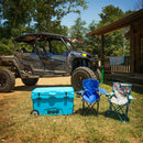 A Bob - The Cooler Co. 75QT / 70.97L "BFF" Hard Cooler with extra thick insulated walls, two folding chairs, and an off-road vehicle are set up outside a wooden cabin on a sunny day, surrounded by green trees.