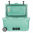 A spacious teal Bob The Cooler Co. 75QT "BFF" Hard Cooler stands open, featuring heavy-duty wheels on one side. The front displays the BOB name with a lightning bolt logo, while "Bob’s Cool" is embossed inside the lid. With extra thick insulated walls, this cooler by Bob - The Cooler Co. keeps contents chilled for hours on end.