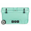 A teal Bob - The Cooler Co. "BFF" 75QT hard cooler with extra-thick insulated walls, two black latches, a small heavy-duty wheel on the left side, and the word BOB—featuring a lightning bolt inside the O—in black lettering on the front.