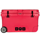 A red Bob The Cooler Co. 75QT "BFF" Hard Cooler on heavy duty wheels, labeled "BOB" in black letters, featuring extra thick insulated walls, a front handle, and two latches securing the lid.
