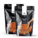 Two black resealable bags of The Spice Lab Rosemary Roasted Garlic Seasoning feature a front design with a wooden spoon and an image of the seasoning blend, accented by white text and leaf graphics. This savory blend from The Spice Lab offers an Italian-inspired flavor profile, making it ideal for enhancing your favorite dishes.