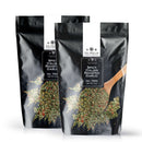 Two black, resealable pouches of The Spice Lab Spicy Italian Roasted Garlic Seasoning are displayed, each featuring a wooden spoon and an herb blend on the packaging. This bold seasoning from The Spice Lab is ideal for grilling and adds robust garlic flavor to your favorite dishes.