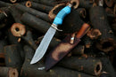 The Texan Knives Hand Made Damascus Steel Hunting and Camping Knife features a blue handle, patterned blade, and comes with an original embossed leather cover—perfect as a gift for him or Christmas.
