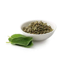 A white bowl filled with The Spice Lab Organic Rubbed Sage sits next to three fresh sage leaves on a white background.