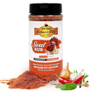 A container of Hickman's BBQ Sweet Natural Gluten Free BBQ Rub 9.4 oz is displayed with seasoning spilled beside it and fresh onion, garlic, chili pepper, herbs, and tomato arranged nearby.