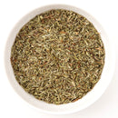 A white bowl filled with The Spice Lab Savory Whole Leaf 1 lb dried thyme is shown from above on a white background, making it ideal for foodservice herbs or BBQ seasoning applications.