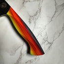 The Spaceman Knives EM Wave Chef Knife features a vibrant gradient handle in red, orange, and yellow tones, resting on white marble with gray veins—ideal for any professional kitchen.