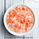 A white bowl filled with The Spice Lab Himalayan Pink Salt Coarse Grain crystals sits on a light wooden surface. Text below the bowl reads, The Spice Lab.