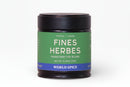 A jar of World Spice Fines Herbes from World Spice, featuring a green label marked “Fines Herbes Handcrafted Blend,” comes with a black lid and set against a white background. This dried herb blend, weighing 0.46 oz (13g), is perfect for elevating French cuisine.