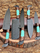 The Texan Knives Premium Knofe Set features five handcrafted 13" forged stainless steel blades, wenge wood and turquoise resin handles, displayed upright on a tree stump with leather sheaths and straw in the background.