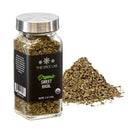 A glass jar from The Spice Lab Organic Starter Spice Set—one of six essential jars in this collection—sits labeled “Organic Sweet Basil” next to a small pile of dried basil leaves on a white background.