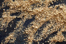 Wood shavings and sawdust scattered on a dark surface create a textured, uneven pattern with small granules and wood particles visible, reminiscent of the earthy blends found in World Spice Adobo by World Spice.
