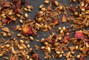 A close-up of World Spice Advieh by World Spice, showcasing a vibrant mix of coriander seeds, dried rose petals, cinnamon bark, cloves, and other aromatic spices scattered on a dark surface—an essential and fragrant blend in Iranian cuisine.