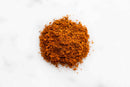 A small mound of World Spice Berbere, a reddish-brown Ethiopian blend from World Spice, on a white surface.