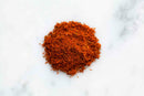 A small pile of World Spice Cajun Black by World Spice is displayed on a white marble surface.