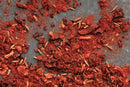 A close-up of scattered World Spice Ancho Chili Powder mixed with whole cumin seeds on a dark surface, showcasing the mild heat and deep color characteristic of this World Spice blend.