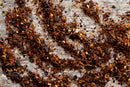 World Spice Chimichurri Spice by World Spice, with its vibrant crushed red pepper flakes inspired by classic Argentinian blends, is scattered across a textured wooden surface.