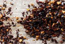 World Spice Chipotle Chile Flake scattered on a rustic wooden surface.