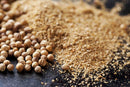 World Spice European Coriander Seed, both whole and freshly ground, are arranged on a dark background to showcase the striking contrast between the round World Spice seeds and their finely milled powder.