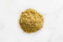 A small mound of finely ground, light brown World Spice Cuban Spice sits on a white surface, bringing to mind the essence of a classic Cuban blend.