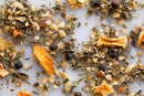 A close-up of World Spice Cuban Spice by World Spice, featuring a blend of dried orange peels, juniper berries, cumin seeds, and dried onion pieces—authentic ingredients scattered on a white surface that capture the essence of classic Cuban flavors.