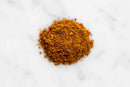 A small mound of finely ground, orange-brown World Spice Kashmiri Curry, brimming with aromatic spices, sits on a white marble surface.