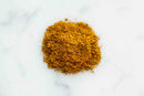 A mound of World Spice Madras South Indian Curry, known for its balanced heat, is spread on a white marble surface.