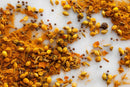 A vibrant assortment of whole and ground spices, such as mustard seeds, coriander seeds, fennel seeds, black peppercorns, turmeric powder, and a touch of yellow curry powder from World Spice Madras South Indian Curry by World Spice is artfully scattered on a white surface, capturing the balanced heat of this classic curry blend.