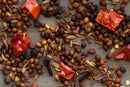 A vibrant assortment of whole spices—featuring brown seeds, red dried chili pieces, cloves, and fennel seeds—essential for authentic Sri Lankan curry, from World Spice Sri Lankan Curry by World Spice, displayed on a wooden surface to showcase their robust flavor blend.