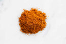 A small pile of World Spice Tandoori Curry powder, an orange-brown spice blend from World Spice often used as a seasoning for Indian dishes or tandoor marinades, rests on a white surface.