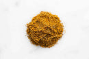 A small mound of finely ground, golden-yellow World Spice Vadouvan Curry blend sits on a white background, evoking the vibrant seasonings characteristic of Puducherry’s French Indian curries.