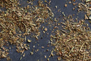 World Spice Italian Herbs by World Spice are scattered on a dark gray surface, showcasing a lively mix of green and brown leaves with thin stems—a vibrant addition to any spice pantry.