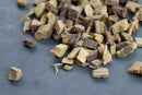 Pieces of World Spice Licorice Root by World Spice, prized for their complex flavor, are scattered on a dark gray surface.