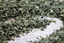 Close-up of loose, dried World Spice Moroccan Mint tea leaves spread across a wooden surface.