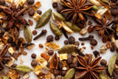 A close-up of World Spice Mulling Spice by World Spice, featuring whole star anise, cardamom pods, allspice, cloves, and dried citrus peel—classic ingredients scattered on a white surface. Perfect for infusing warmth and flavor into mulled cider or mulled wine.
