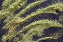 Loose, dried green World Spice Ranch Seasoning by World Spice evokes classic ranch flavors as it is artfully arranged in four curved, parallel lines on a black surface, creating a visually striking and herby pattern.