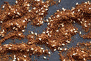 A close-up of a dark surface sprinkled with World Spice Syrian Za'atar from World Spice—a brown, crumbly Middle Eastern spice blend with white sesame seeds scattered throughout.