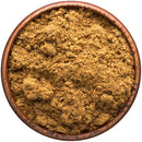 A wooden bowl filled with The Spice Lab Organic Ground Nutmeg, viewed from above on a white background—perfect for holiday baking or adding a warm touch to eggnog.