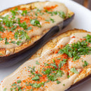 Two roasted eggplant halves topped with a creamy sauce, chopped fresh herbs, and a sprinkle of The Spice Lab Ghost Pepper Powder for extreme heat, served on a white plate.