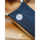 Close-up of the Dalstrong Professional Coarse Wide Cheese Grater with a G10 handle, featuring a circular metal insignia. The background is blurred, and the Dalstrong logo appears at the bottom.