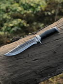 The Texan Knives Best Bowie Knife, featuring a 13" handmade Damascus steel blade and resin horn handle, is displayed on a weathered tree trunk outdoors with blurred green foliage in the background.