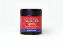 A 2.75 oz jar of World Spice Rooster Spice handcrafted blend from World Spice, featuring a red and blue design and labeled with “Heat • Umami • Picante” and “World Spice.” Infused with spicy chili powder inspired by Southeast Asian cuisine, the jar is set against a plain white background.