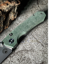 Close-up of the Spaceman Knives N1 EDC by Spaceman Knives, featuring a textured green Micarta handle, resting on rough stone. Tree bark is visible in the top left corner.