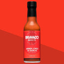 A 5 fl oz bottle of Bravado Spice Co Árbol Chili & Garlic Hot Sauce, featuring a red label, is displayed against a two-tone red background. This medium-heat hot sauce from Bravado Spice Co combines the bold flavors of garlic and fiery Árbol chili peppers in a flavorful Mexican-inspired blend.