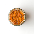 Top view of a glass jar filled with Taycte Famiglia Crispino Spicy Arrabbiata Bruschetta Spread — Hot Pepper Italian Antipasto, showing its chunky orange-brown texture, placed on a white background.