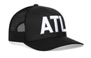The Haka Hat Atlanta White Block Trucker Hat is a black mesh snapback with large white "ATL" embroidery on the front.