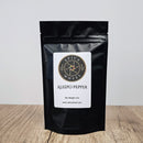 A black resealable bag labeled Spice Wheel Aleppo Pepper 1/4 lb from Spice Wheel rests on a wooden surface against a plain light background.